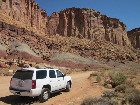 1991 Ford LTD Crown Victoria - A white SUV is parked on a dirt road in a desert landscape with large red rock formations.