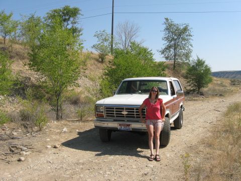 1981 Ford Bronco - Woman poses with a 1980 Ford Bronco on a dirt road with dry brush and trees.