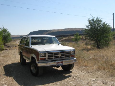 1981 Ford Bronco - This 1980 Ford Bronco is shown from a three-quarter front view on a dirt road with dry grass and hills in the background.