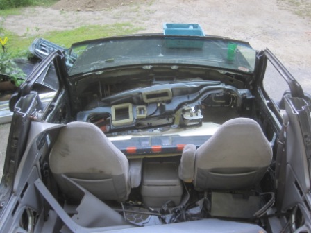1993 Ford Bronco - The interior of a vehicle is shown with its dashboard and seats removed, revealing the internal structure and wiring.