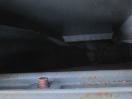 1993 Ford Bronco - A close-up view of a bolt and a dark, possibly interior, panel of a vehicle.