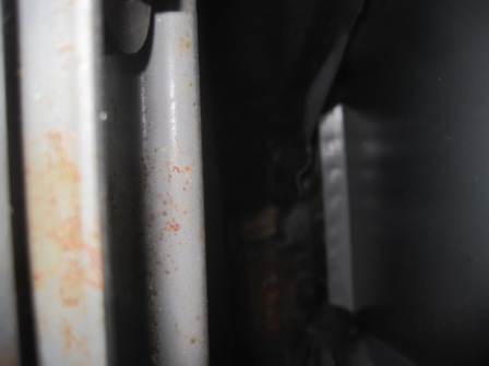 1993 Ford Bronco - Close-up view of weathered metal components, showing rust and a dark, indistinct background.