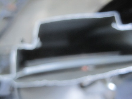 1993 Ford Bronco - Detail of a vehicle's structural component, showing a white-lined metal edge against a dark background.