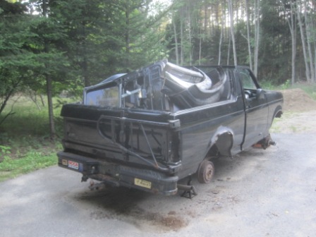 1993 Ford Bronco - This black pickup truck is missing its wheels and appears to be in a state of disrepair.