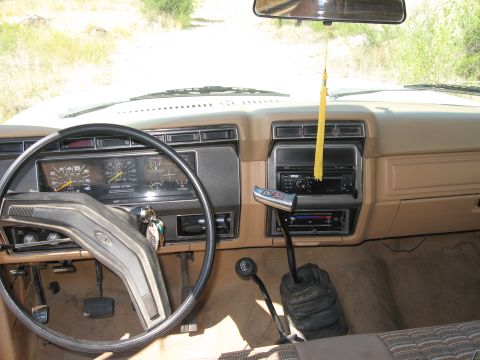 1981 Ford Bronco - Dashboard and interior of a 1980s Ford truck, a manual transmission and aftermarket radio.