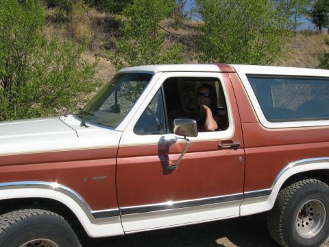 1981 Ford Bronco - A woman smiles from the driver's seat of a two-tone brown and white 1981 Ford Bronco.