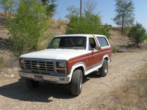 1981 Ford Bronco - This 1980 Ford Bronco is seen from the front-right on a dirt path with trees in the background.