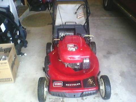 1996 Ford F-150 - A red Toro Recycler lawnmower with a Briggs & Stratton 675 engine is parked in a garage.
