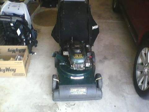 1996 Ford F-150 - A Craftsman lawn mower is parked indoors next to a box and a vehicle.