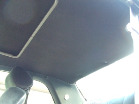 1996 Ford Bronco - Interior view of a car's headliner and sunroof frame, with a portion of a headrest in the foreground.