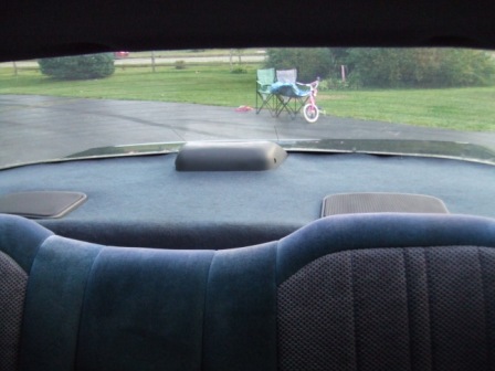 1996 Ford Bronco - View from the rear seat looking out through the back window at a backyard with a bicycle and chairs.
