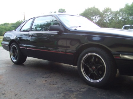 1996 Ford Bronco - Side view of a black Ford Thunderbird Super Coupe with red pinstriping and aftermarket wheels.