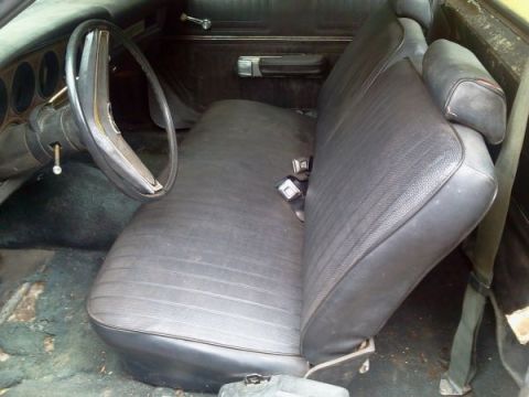 1974 Ford Ranchero - The interior of an old car shows a bench seat, steering wheel, and door panel.