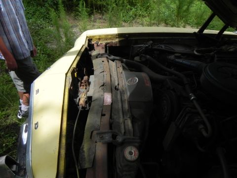 1974 Ford Ranchero - Engine bay of a yellow car, showing the radiator and engine components under the open hood.