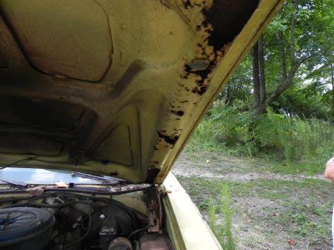 1974 Ford Ranchero - The underside of the hood shows significant rust damage, with the engine bay visible below.