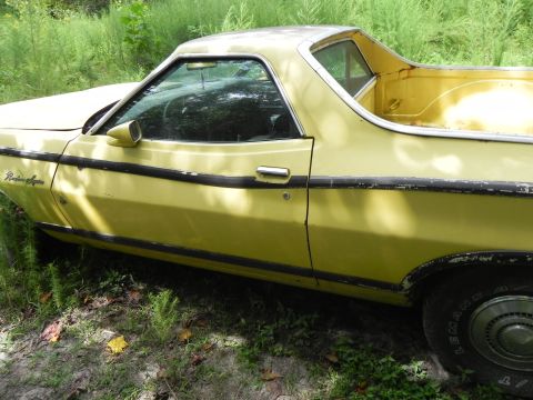 1974 Ford Ranchero - A yellow Ford Ranchero with black trim is parked outdoors in tall grass.