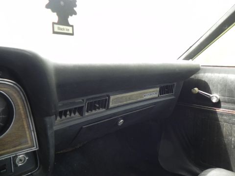 1974 Ford Ranchero - The interior of a car features a dashboard with air vents and a chrome door handle, along with a 'Black Ice' air freshener.