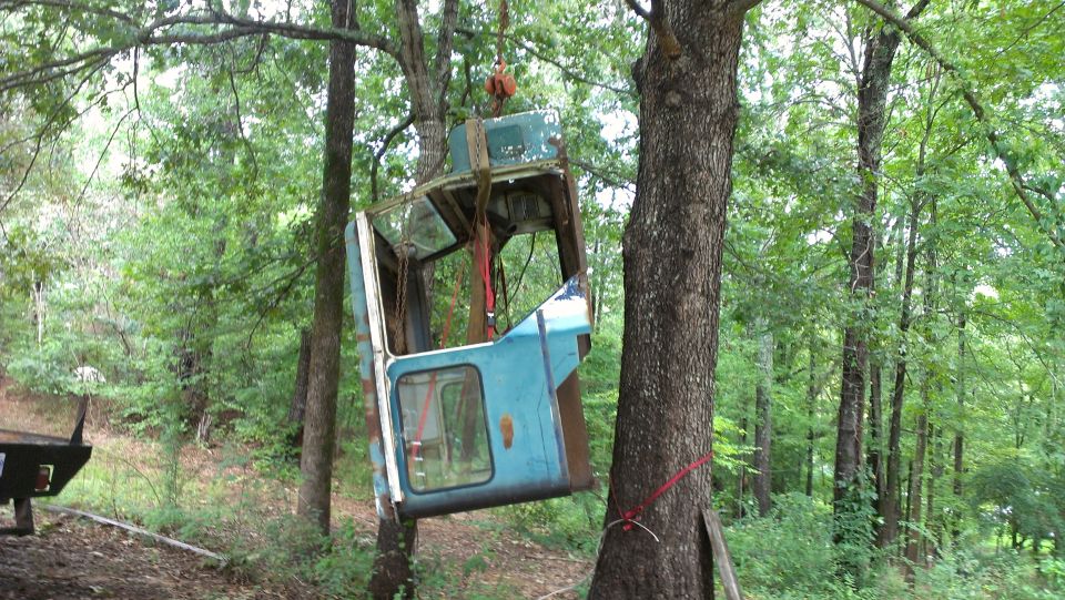 Blue truck cab hanging from tree, Supermotors.net logo visible
