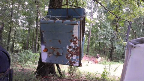 1978 Ford Bronco - This appears to be a truck cab, possibly from an older model, suspended from a tree.