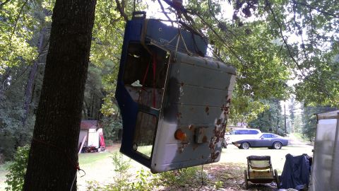 1978 Ford Bronco - A detached truck cab is suspended from a tree, with other vehicles visible in the yard.