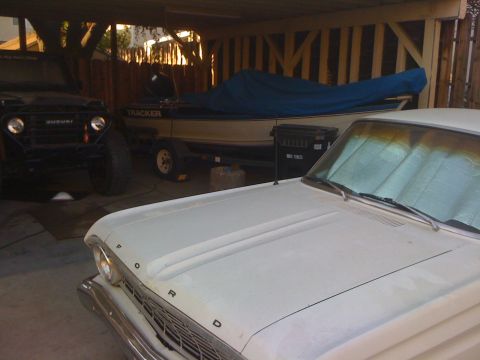 1987 Suzuki Samurai - A black Suzuki Samurai is parked next to a boat on a trailer and a white Ford car.