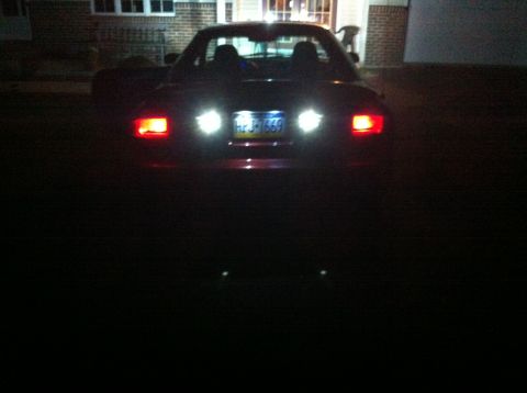 1994 Ford Probe - The rear of a red convertible sports car is illuminated by its taillights and brake lights at night.