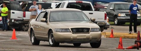 2000 Mercury Grand Marquis - A gold sedan is seen from the front in a parking lot, with traffic cones indicating a course.