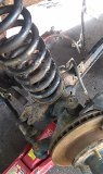 1979 Ford Bronco - Close-up view of vehicle suspension components, including a coil spring and brake rotor, undergoing maintenance.