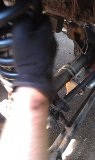 1979 Ford Bronco - Mechanic's gloved hand works on the rear axle and suspension components of a vehicle.