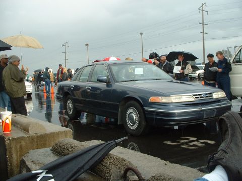 1999 Ford Crown Victoria - Dark blue 1999 Ford Crown Victoria at an outdoor auction on a rainy day.