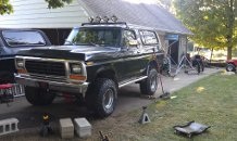 1979 Ford Bronco - This black SUV appears to be undergoing rear axle maintenance, with its suspension lifted by a jack.