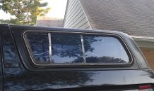 1979 Ford Bronco - Side view of a truck cap with a sliding window, showing reflections of the surroundings.