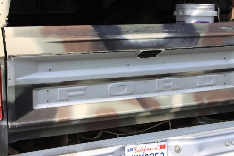 1979 Ford F-350 - The tailgate of a Ford truck displays the brand name and a camouflage paint scheme.