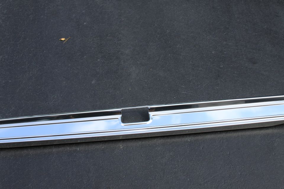 Chrome trim piece with a black rectangular insert, likely from a vehicle's exterior