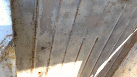 1978 Ford Bronco - Close-up of a heavily rusted and weathered metal panel, showing ribbed texture.