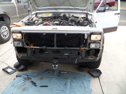 1994 Jeep Cherokee - Front view of a 1994 Jeep Cherokee with the hood open, undergoing maintenance. Tools are laid out on a blue cloth.