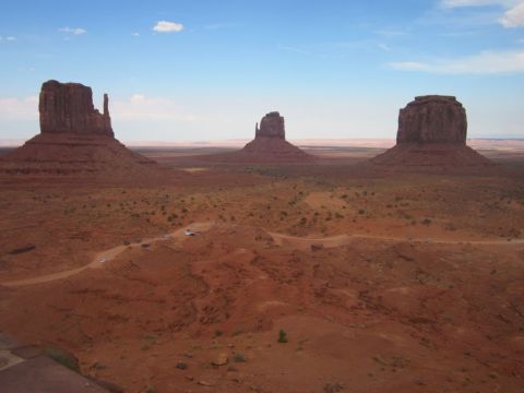 1991 Ford LTD Crown Victoria - Monument Valley's iconic buttes stand tall against the desert sky, with a road visible below.