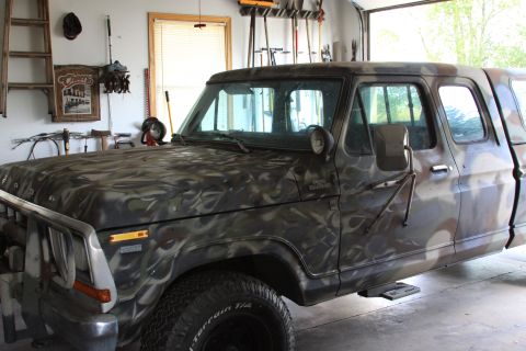 1979 Ford F-350 - This 1979 Ford F-350 truck features a unique camouflage paint job and is seen from the side in a garage setting.