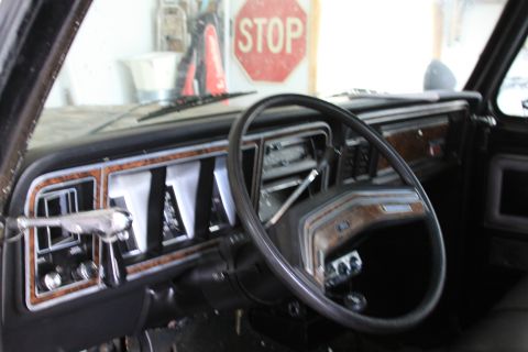 1979 Ford F-350 - Interior view of a 1979 Ford F-350 dashboard, wood grain accents and a STOP sign visible in the background.