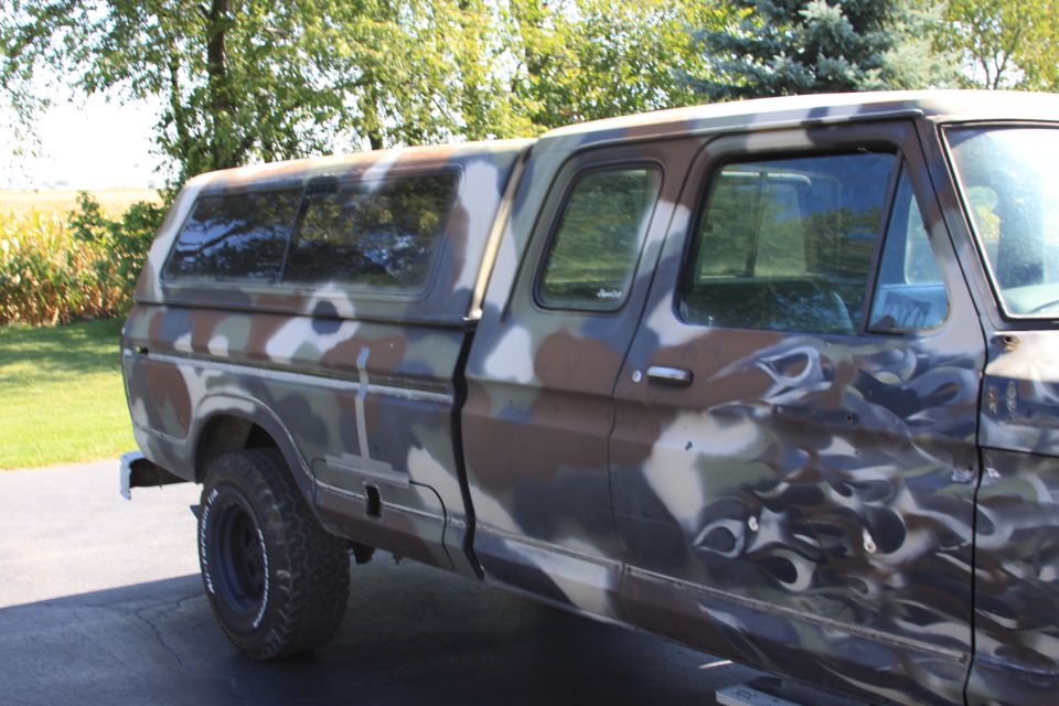 Side view of a 1979 Ford F-350 pickup truck with camouflage paint and a camper shell