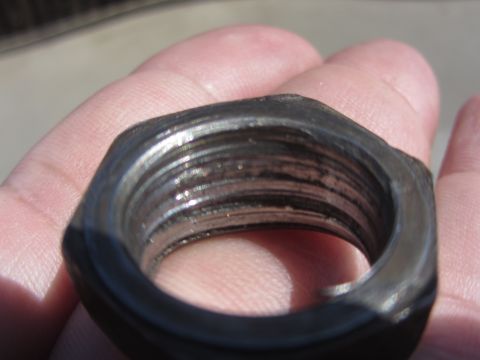 1964 Ford Ranchero - A hex nut with internal threads is held in a hand, showing wear and grime on its surfaces.