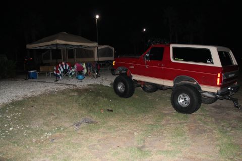 1990 Ford Bronco - Red 1990 Ford Bronco with lifted suspension at a campsite during the night.