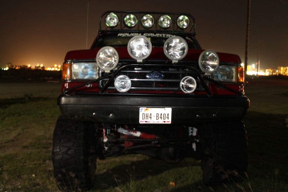 Red Ford truck, front view, with multiple off-road lights and a light bar. License plate DH4-B404