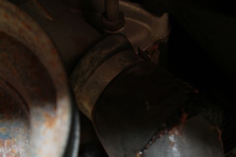 1990 Ford Bronco - A close-up view shows a corroded exhaust pipe and its securing clamp.