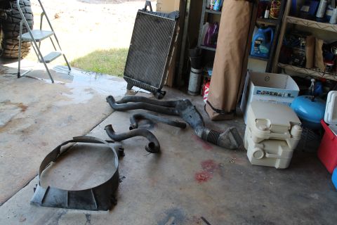 1990 Ford Bronco - Various engine parts, including a radiator and hoses, are visible on the floor of a garage.