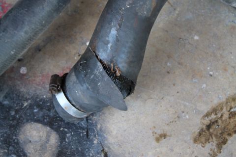 1990 Ford Bronco - A cracked radiator hose is shown with a metal clamp, indicating a potential leak or failure.