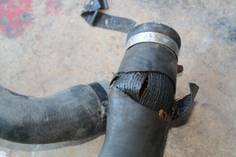 1990 Ford Bronco - This radiator hose has a significant split, exposing the internal reinforcement and a clamp.