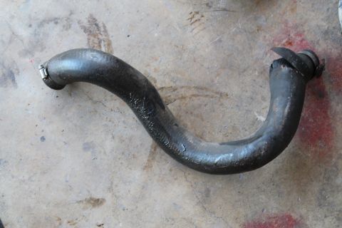 1990 Ford Bronco - A single automotive radiator hose is shown resting on a concrete surface.