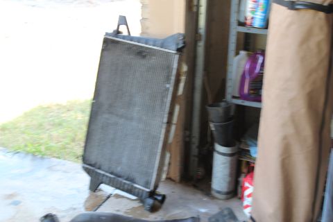 1990 Ford Bronco - A radiator is shown leaning against a wall, with various items on shelves behind it.