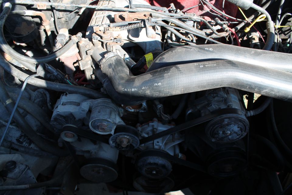 Engine bay with hoses, belts, and alternator visible. Text on hose reads 'CA11BN AU R6'